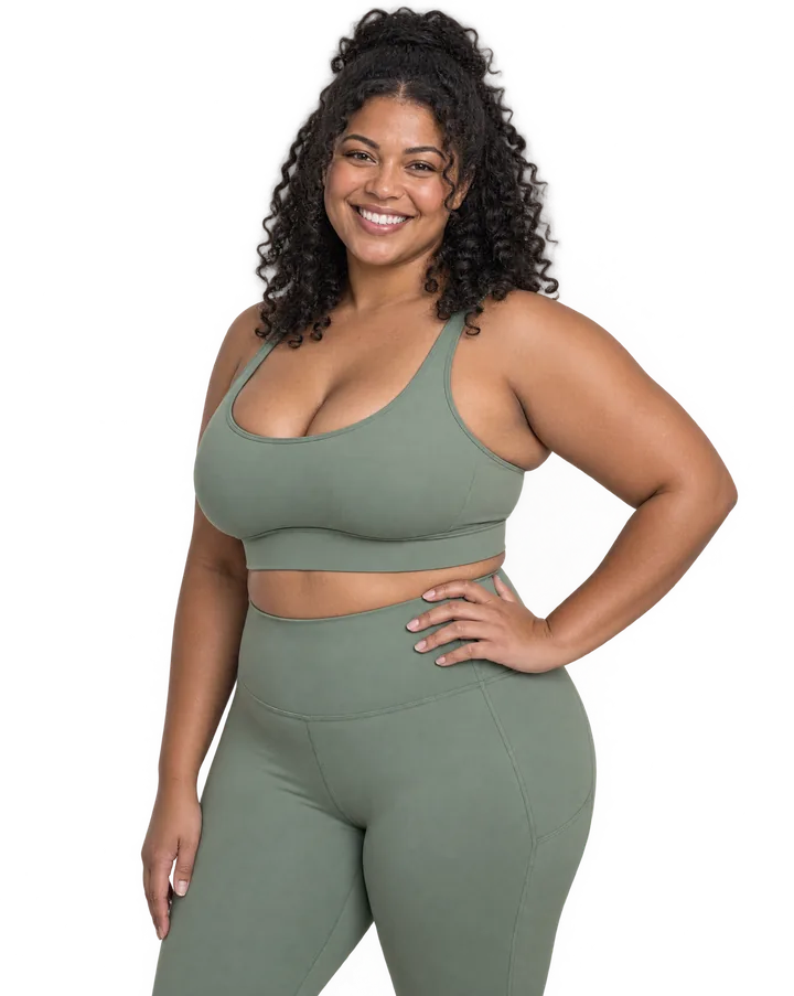 Smiling woman in a sage sports set with her hand on her hip
